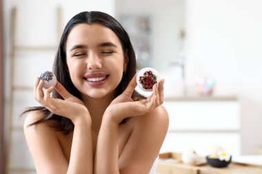 Banyoda banyo bombaları olan mutlu genç bir kadın.