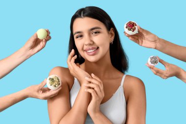 İç çamaşırlı güzel bir kadın ve mavi arka planda banyo bombaları olan kadın elleri.