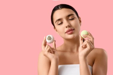 Pembe arka planda banyo bombaları olan iç çamaşırlı güzel bir kadın.