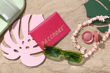 Plaj aksesuarları ve kum üzerinde palmiye yaprakları olan pasaport.