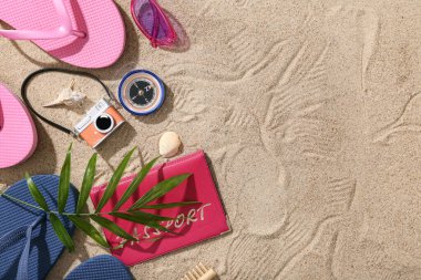 Plaj aksesuarları ve kum üzerinde palmiye yaprağı olan pasaport.