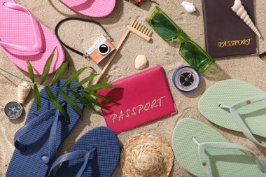 Plaj aksesuarları ve kum üzerinde palmiye yaprağı olan pasaport.