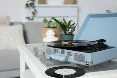 Oturma odasındaki masada vinil diskleri olan kayıt çalar, yakın plan.