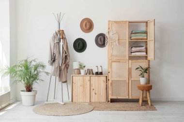 Odanın içinde ahşap dolap, elbise askısı ve şapkaları var.