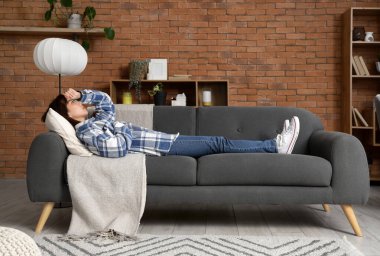 Evdeki kanepede yatan intihara meyilli genç Asyalı kadın.