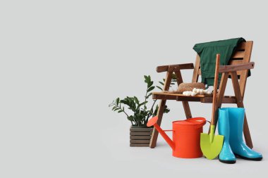 Tahta koltuk, bitkiler ve beyaz arka planda bahçe malzemeleri.