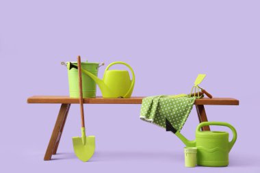 Leylak arka planında bahçe malzemeleri olan bankta.