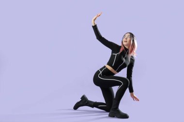 Eflatun arkaplanda VR gözlükleri olan fütüristik kostümlü genç bir kadın.