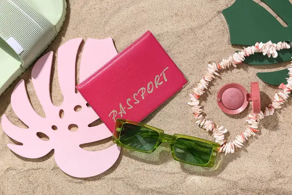 Plaj aksesuarları ve kum üzerinde palmiye yaprakları olan pasaport.