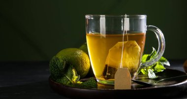 Koyu arkaplanda limonlu sıcak çay ve nane şekeri, yakın plan.