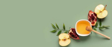 Rosh Hashanah kutlaması için bir kase bal, nar ve elma (Yahudi Yeni Yılı) yeşil arka planda