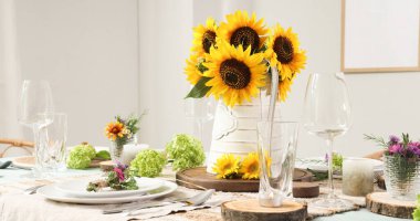 Güzel ayçiçekleri, çiçek dekoru ve mumlarla servis edilen yemek masası.