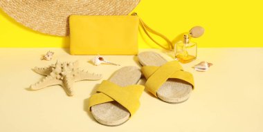 Sarı duvarın yanında hasır şapkalı ve parfümlü sandaletler