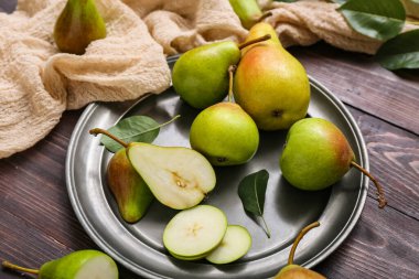 Koyu ahşap masada olgun armutlarla kaplanmış, yakın plan.