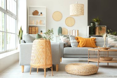 Gri kanepesi, sehpası ve hasır lambası olan bir oturma odası.