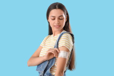 Mavi arka planda uygulamalı doğum kontrol bandı olan genç bir kadın.