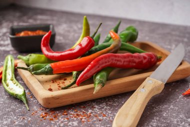 Koyu arka planda taze kırmızı biberli ahşap tahta.