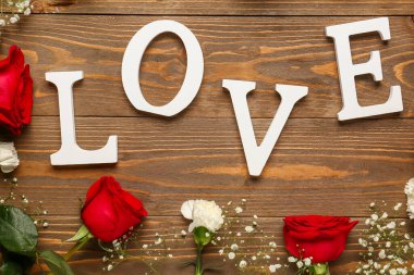 Aşk kelimesi ahşap arka planda güzel çiçekler çerçevesinde
