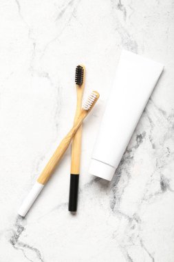 Beyaz grunge arka planda diş macunu ve ahşap diş fırçası tüpü.