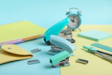 Renk arkaplanına farklı okul kırtasiyesi, zımba zımbası ve alarm saati