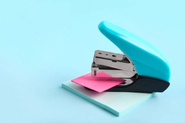 Renk arkaplanı üzerine yapışkan notları olan mavi zımba.