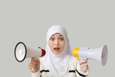 Gri arka planda megafonlarla genç Asyalı Müslüman kadını şoke etti. Ulusal Duyulma Günü