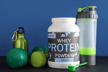 Renkli arka planda protein tozu ve spor malzemesi bulunan şişe