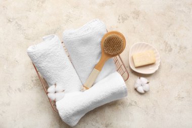 Temiz yumuşak havlular, vücut masajı fırçası ve arkaplanda metal kutuda pamuk çiçekleri.