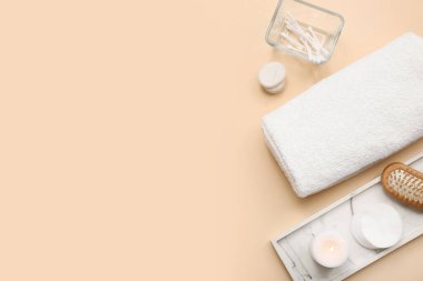 Sarılmış yumuşak havlu, taş tepsi, pamuk yastık ve bej arkaplanda mum kompozisyonu