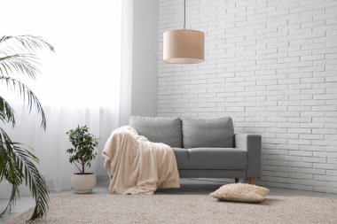 Gri kanepesi, çiçekleri ve ışık perdeleri olan şık bir oturma odası.