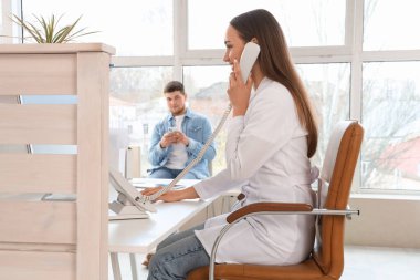 Klinikteki masada telefonla konuşan kadın resepsiyonist.