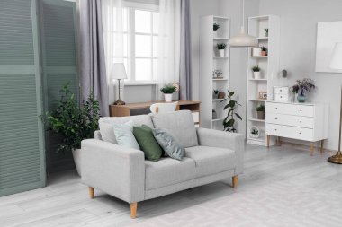 Yeşil perdeli, kanepeli ve raf üniteli oturma odasının içi.