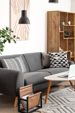 Siyah kanepesi, sehpası, dizüstü bilgisayarı ve raf ünitesi olan şık bir oturma odası.