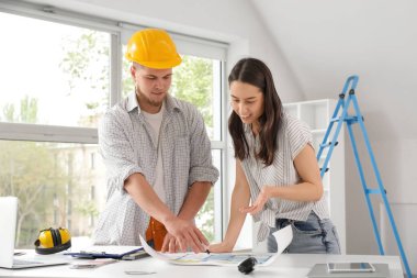 Müşteri ile müteahhit odada ev planını tartışıyor.