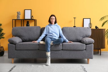 Aydınlık oturma odasındaki kanepede oturan genç kadın.