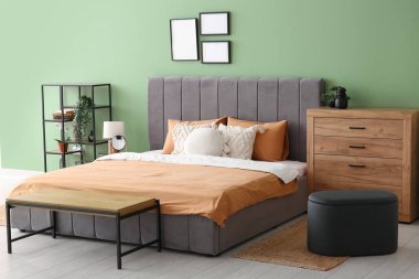 Rahat yatak, yastıklar ve şık yatak odasında ahşap çekmeceler.