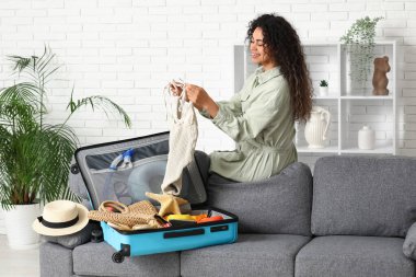 Evdeki valizlerden yaz kıyafetlerini çıkaran güzel genç bir kadın.
