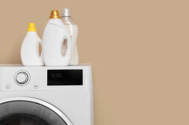 Bej arka planda deterjanları olan modern çamaşır makinesi, yakın plan