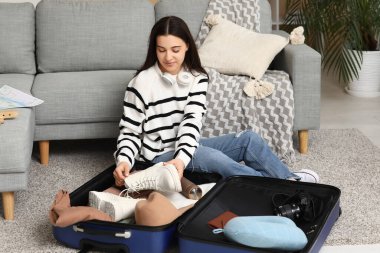 Evde bavulunu toplayan genç bir kadın. Seyahat kavramı