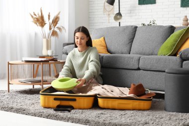 Evinde yerde yastığı valize koyan genç bir kadın. Seyahat kavramı