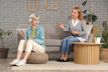 Psikologun ofisinde cep telefonu kullanan kulaklıklı genç bir kız.