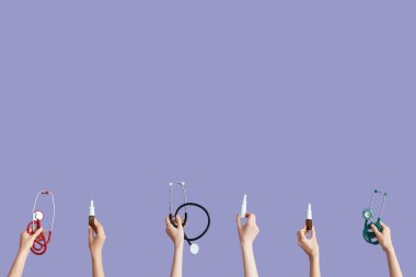 Steteskoplu eller ve leylak arkaplanda burun spreyleri.