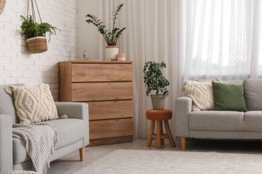 Rahat kanepeleri, çekmeceleri ve çiçekleri olan güzel bir oturma odası.