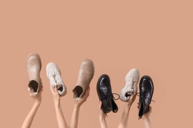 Bej arka planda kadın eli çizme ve spor ayakkabısı.