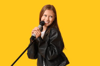 Sarı arka planda modern mikrofonu olan tatlı bir kız.