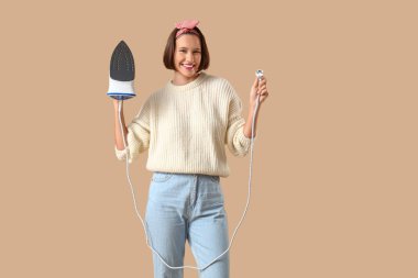 Bej arka planda demiri olan gülümseyen genç bir kadın.