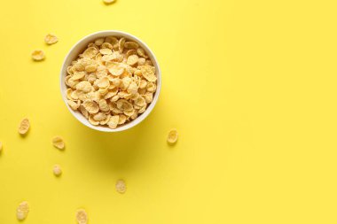 Sarı zemin üzerinde sağlıklı mısır gevreği olan bir kase.