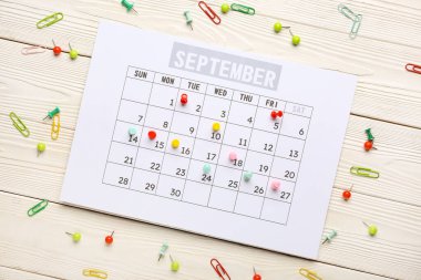 Beyaz ahşap arka planda ataç ve raptiyeli takvim. Planlama kavramı