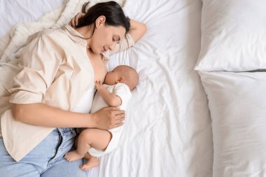 Genç anne bebeğini yatakta emziriyor.