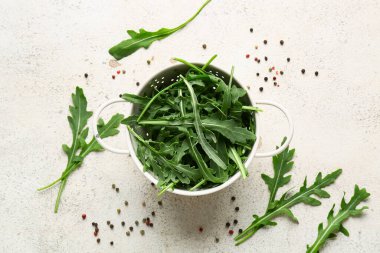 Beyaz arka planda taze roka yaprakları ve biberli Colander.